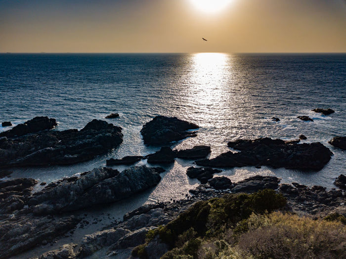 Wide ocean view with a setting sun and a foreground of rocks, wakayama, japan .