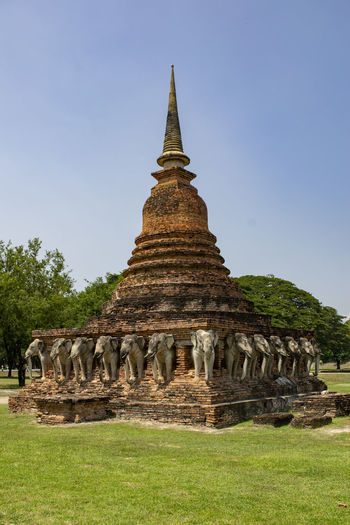 Ruined pagoda on field against clear blue sky