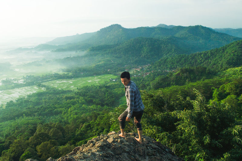 Man standing on cliff against landscape