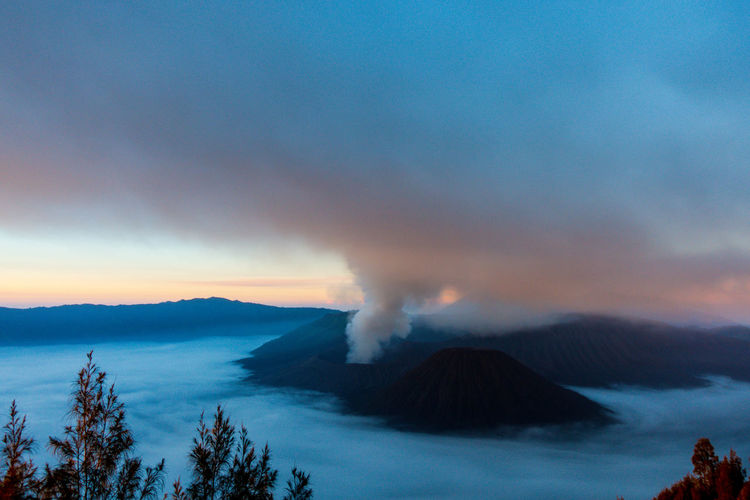 Active volcano at mt bromo against cloudy sky during sunset