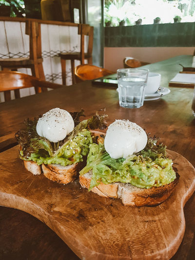 Freshly made avocado toast with poached eggs on table.