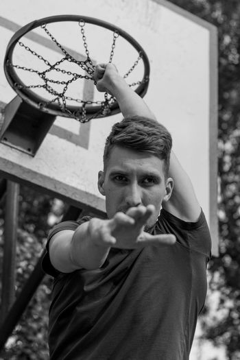 Portrait of young man holding basketball hoop