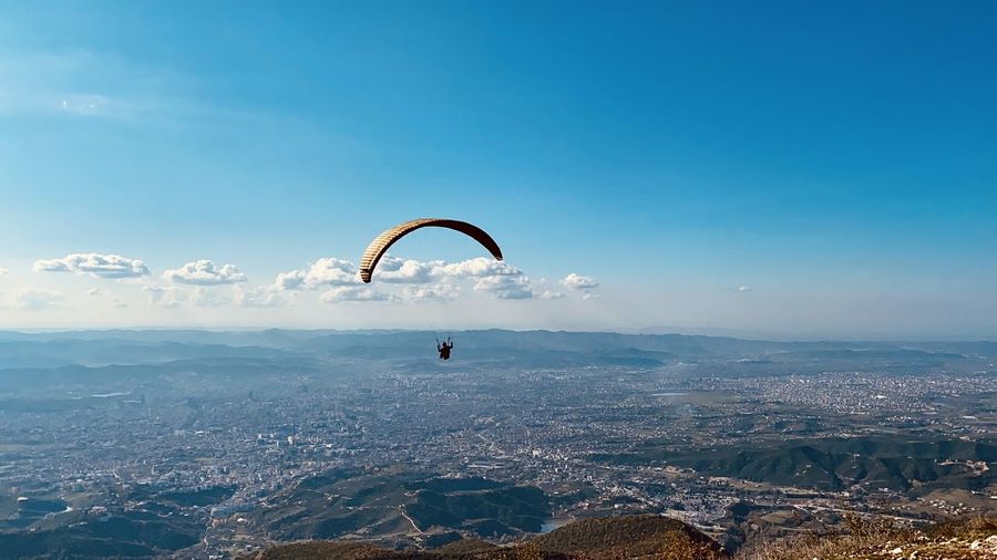 People paragliding over tirana cityscape against sky