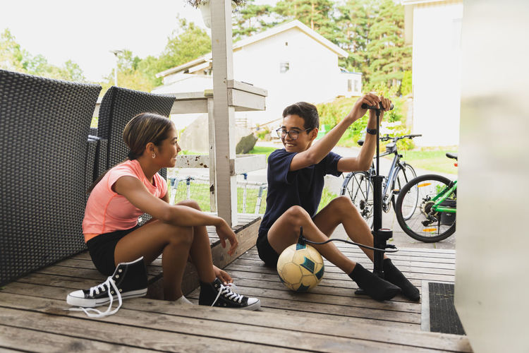 Brother and sister preparing to play football sitting on porch