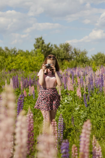 Rear view of woman standing amidst purple flowering plants on field