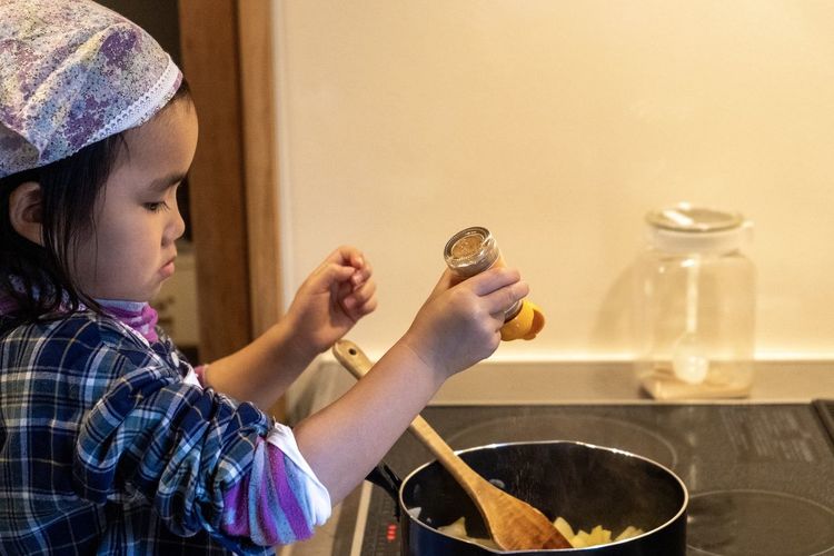 Side view of girl cooking food at home