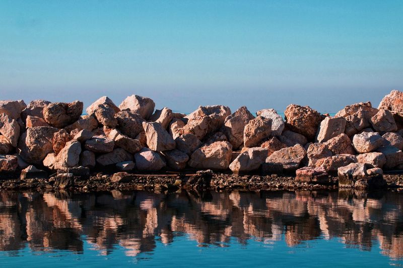 Panoramic view of rocks in sea against clear blue sky