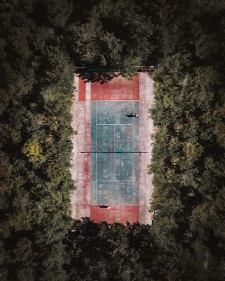 Aerial view of friends playing at sport court against trees in forest