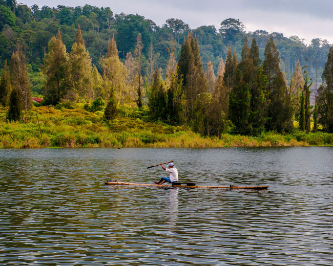 Man in wooden raft on lake