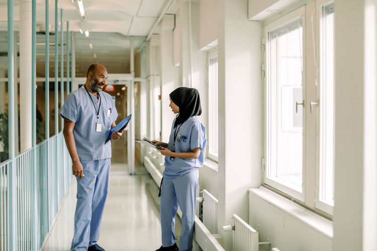 Male and female colleagues talking in corridor at hospital
