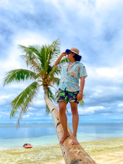 Rear view of woman standing at beach against sky