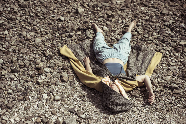 Girl in cloak lays on stones in the sun