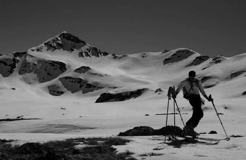 Man skiing on snowcapped mountain against clear sky