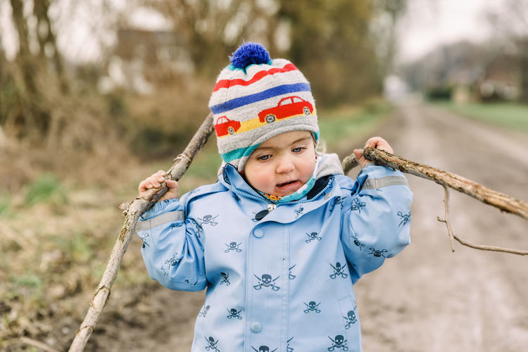 Cute girl wearing warm clothing holding sticks