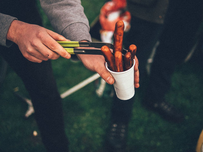 Close-up of man holding sausage in disposable cup