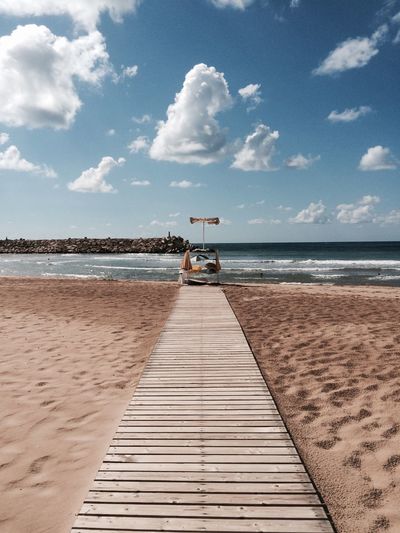 Boardwalk on sandy beach against sky