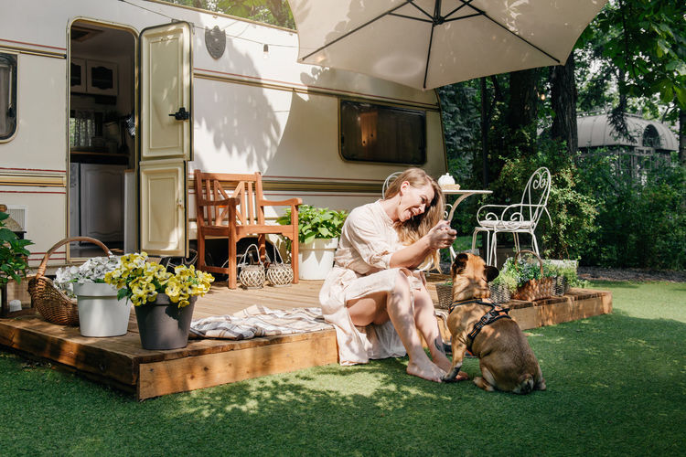 Camping and travelling . happy person relaxing outdoors near trailer. woman with dog is ready for