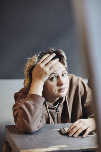 Portrait of teenage girl sitting with head in hands at desk