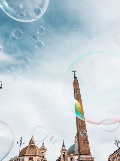 Low angle view of bubbles and building against sky