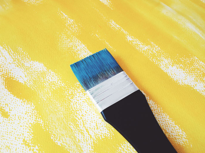 High angle view of paintbrush on yellow fabric