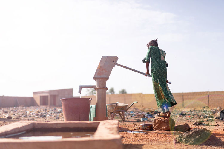 Full length of girl using water pump on land