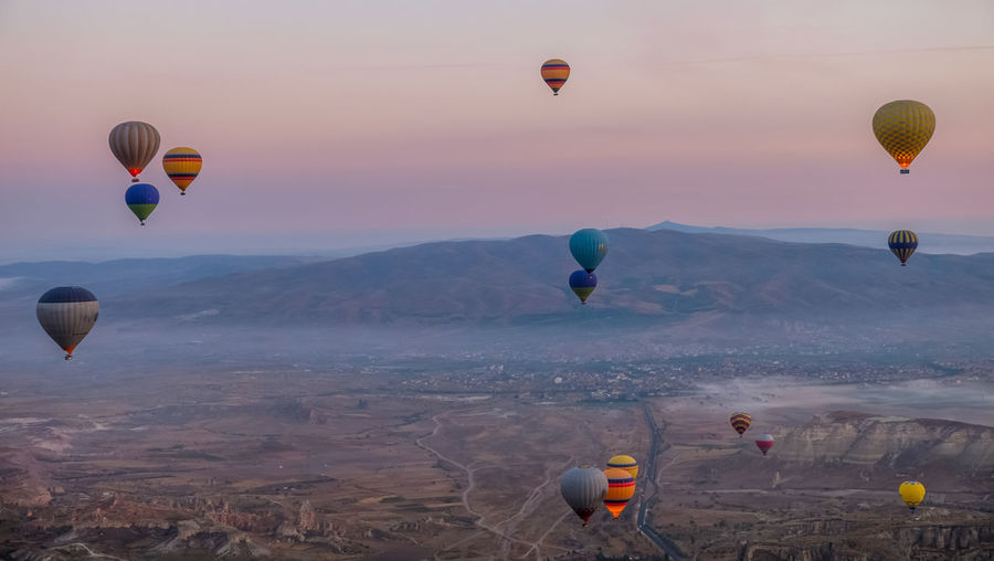 Hot air balloons flying over landscape at cappadocia during sunset