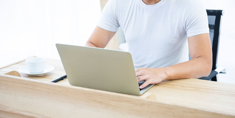 Midsection of man using laptop on table