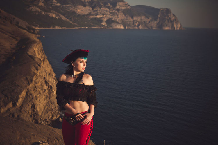 Portrait of a pirate woman at the beach. in anticipation of a pirate ship, sunset