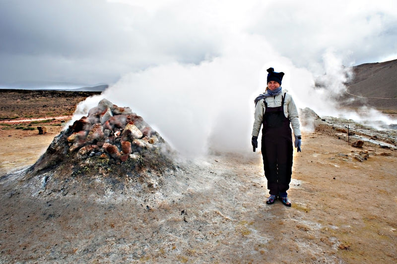 Woman traveling in hverir geothermal area in iceland volcano steaming fumaroles,  alternative energy