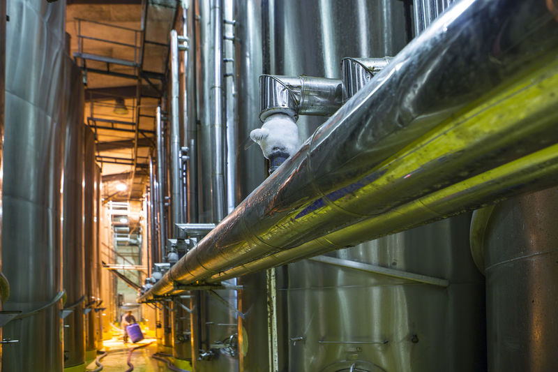 Worker controlling stainless steel tanks for food industry