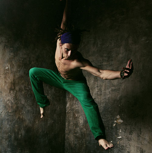 Full length of young man dancing against wall