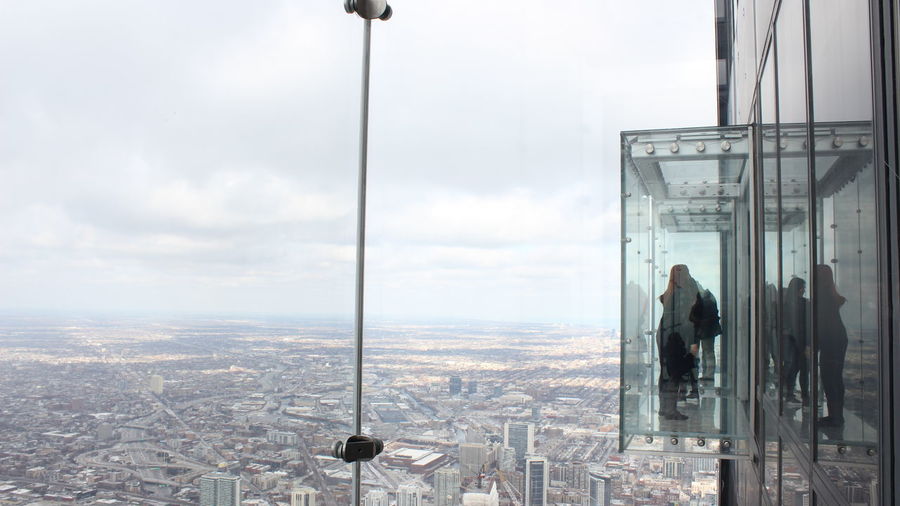 People on skydeck of willis tower with cityscape against sky