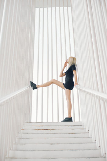 Full length of woman standing on steps amidst railing