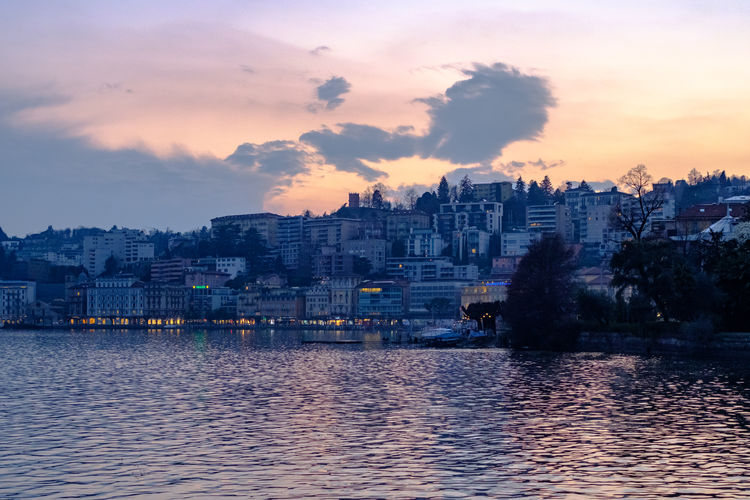 River by buildings against sky at sunset