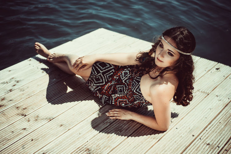 Portrait of young woman lying on pier