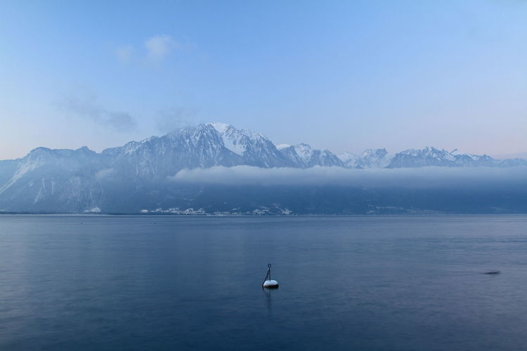 Scenic view of lake geneva and snowcapped mountains against sky