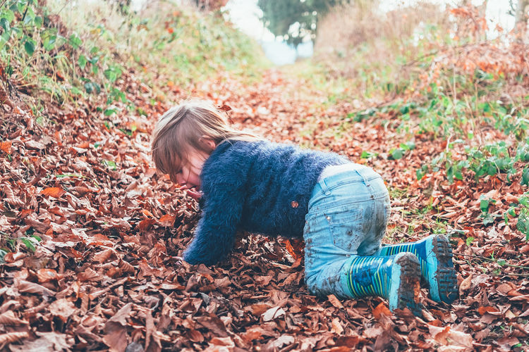 Side view of girl falling on field during autumn