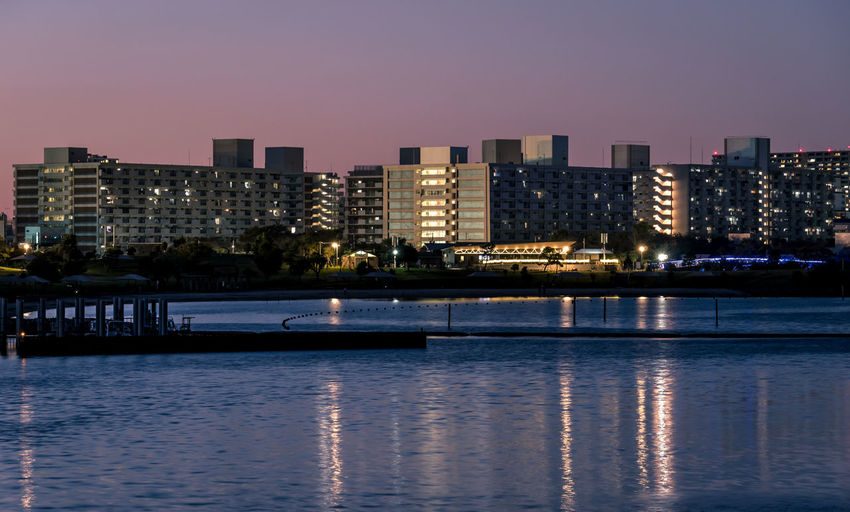 River by illuminated buildings against sky at night