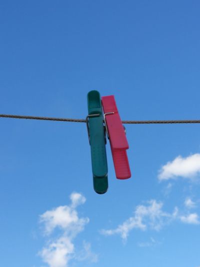 Low angle view of clothespins on clothesline against blue sky