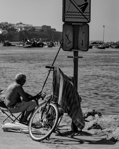 Man sitting on bicycle by sea in city