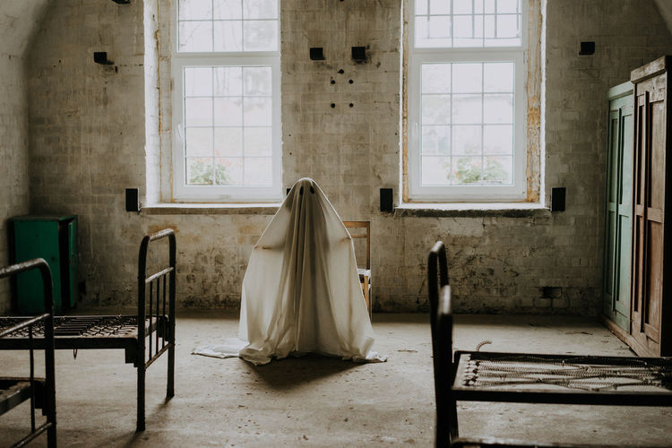 Little ghost standing in the abandoned house. autumn halloween