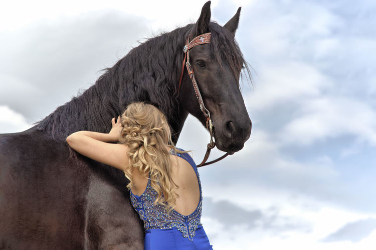 Woman embracing horse while standing outdoors