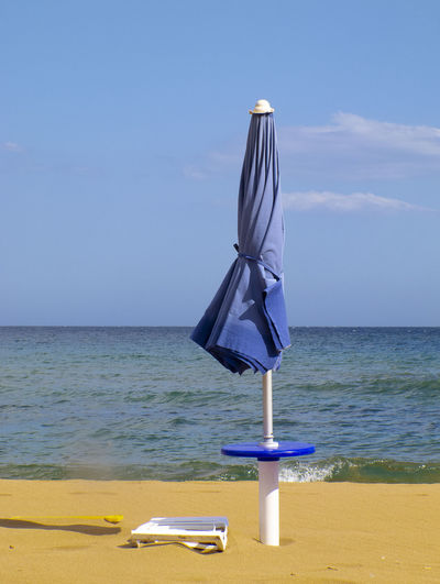 Deck chairs on beach against sky
