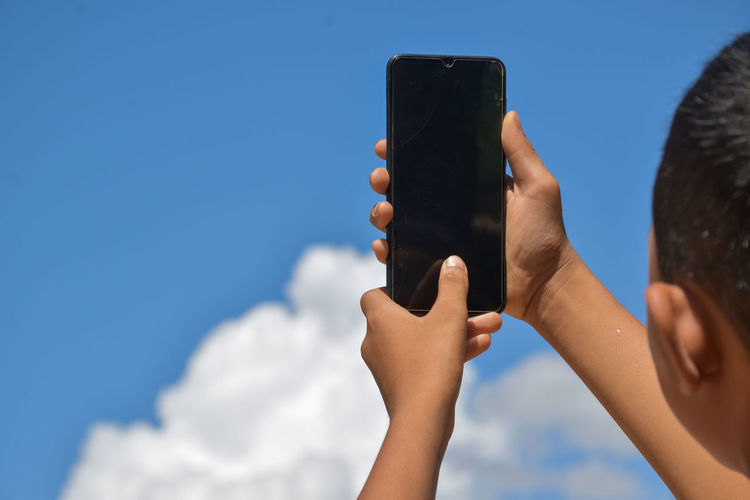 Low angle view of woman using mobile phone against sky