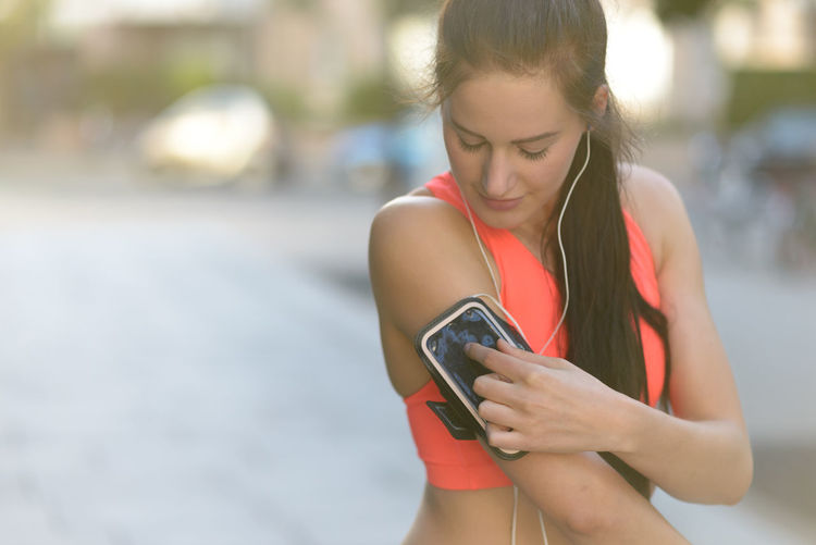 Young woman playing music on her phone for jogging