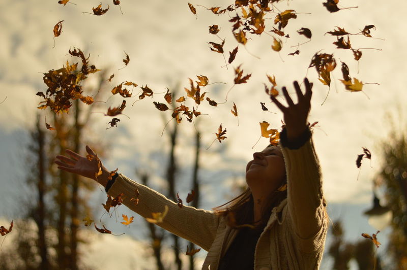 Woman throwing dry leaves