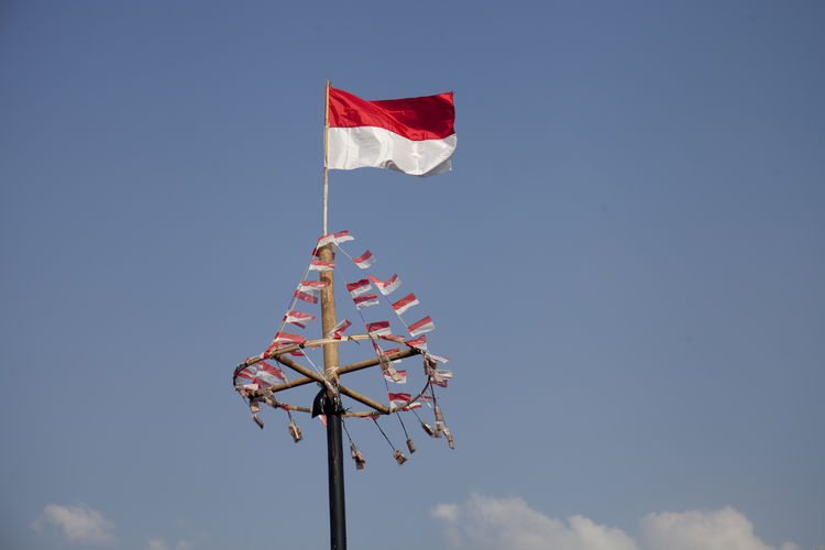 Low angle view of indonesian flag waving against sky