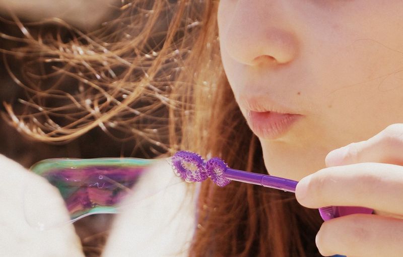 Midsection of woman blowing bubble wand