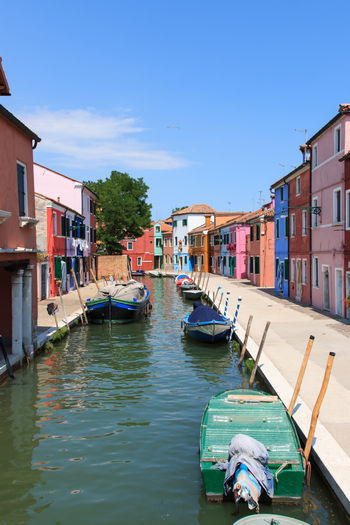 Boats anchored on canal by colorful houses