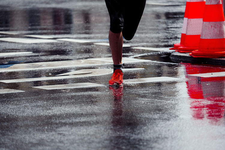 Low section of woman running on wet road